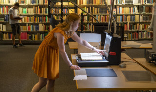 Vrouw met boek op scanner in bibliotheek